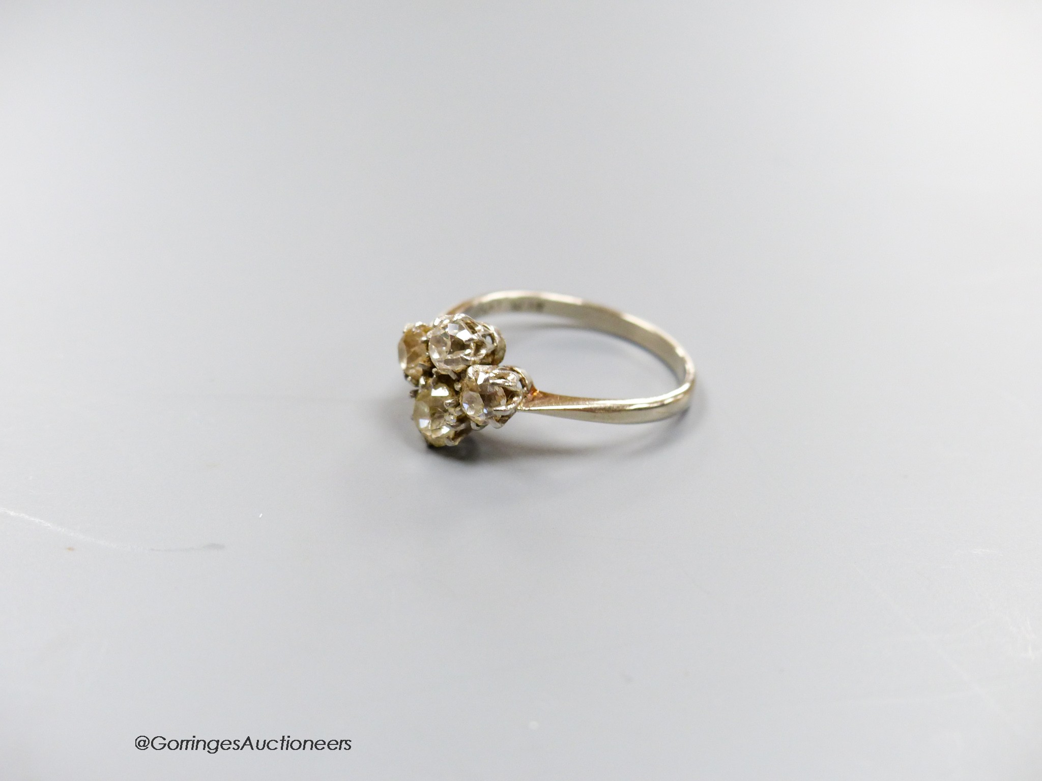 A white metal (stamped plat) and four stone diamond cluster ring, size O/P, gross 3.3 grams.